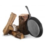a cast iron skillet next to wood logs